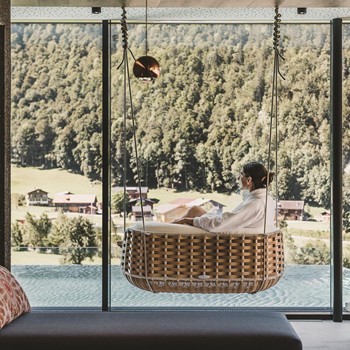 Ruhe finden und die traumhafte Bergkulisse im Spa-Bereich genießen Frau genießt Aussicht im Hängesessel mit Blick auf die Berge.